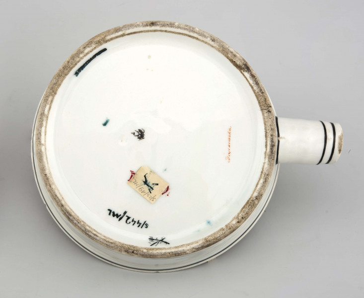 Naczynie stożkowate z uchwytem w postaci szerokiej rurki (służącym do zamocowania drewnianej rączki), pokrywa kopulasta z uchwytem w kształcie rozkwitłej korony kwiatowej. Krawędzie obwiedzione czarnymi paskami, czernią podkreślony modelunek uchwytu. Spód nieszkliwiony.
 