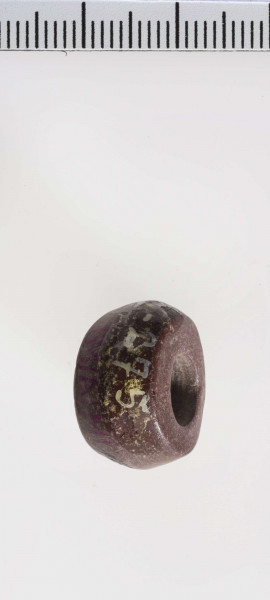 wykonany z łupka owruckiego; dwustożkowy, łagodnie profilowany; przy otworze płasko ścięty; otwór średniej wielkości, cylindryczny