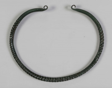 1395/A/ML/1 - Naszyjnik brązowy wykonany z brązowego pręta lanego, pokryta zieloną patyną. Całość spiralnie skręcona; końcówki rozklepane (płasko) i wywynięte na zewnątrz; końcówki naszyjnika gładkie nie skręcane 