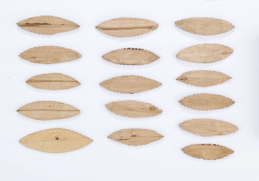 Figurki gry dziecięcej służące do zabawy z podrzucaniem. Wystrugane z drewna w formie płaskich owalnych listków (kształt migdału) o nacinanych brzegach. Składa się z 16 elementów.