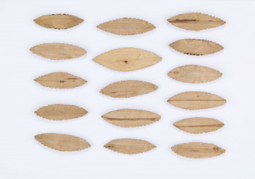 Figurki gry dziecięcej służące do zabawy z podrzucaniem. Wystrugane z drewna w formie płaskich owalnych listków (kształt migdału) o nacinanych brzegach. Składa się z 16 elementów.
