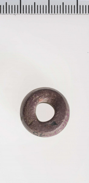 wykonany z łupka owruckiego; dwustożkowy, łagodnie profilowany; przy otworze płasko ścięty; otwór średniej wielkości, cylindryczny