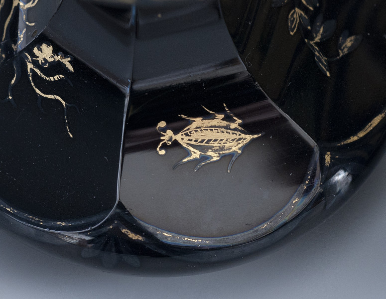 Detal – owal na jednej faset. Złocona dekoracja przedstawia owada o małej główce z czułkami, z zaokrąglonym, wydłużonym korpusem i sześcioma nogami. Owad skierowany jest w lewą stronę.