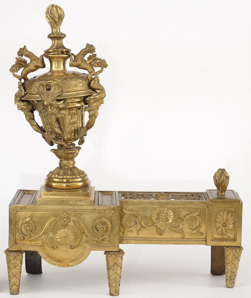 ujęcie z przodu (strona pierwsza). Złoty w kolorze wilk napięciu zbieżnych nóżkach, o masywnej części poziomej, złożonej z dwóch prostopadłościanów. Po lewej stronie widoczny szerszy, stanowiący cokół dla bogato rzeźbionej sterczyny w formie wazy zwieńczonej płomieniem. Po prawej węższy, stanowiący podporę dla polan.