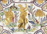 ujęcie z góry - fragment (scena mitologiczna) wieczko. Po prawej stronie tańcząca fama, obok po lewej siedząca postać z tarczą lub lustrem wspartym na kolanach wokół dekoracja roślinna, w lewym rogu zamek.