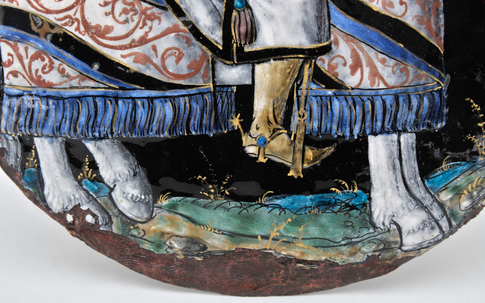 awers – fragment dolny, ujęcie na kopyta końskie i dół końskiego czapraku, z niebieskimi frędzlami, złote ostrogi mężczyzny, uszkodzenia emalii na krawędziach.