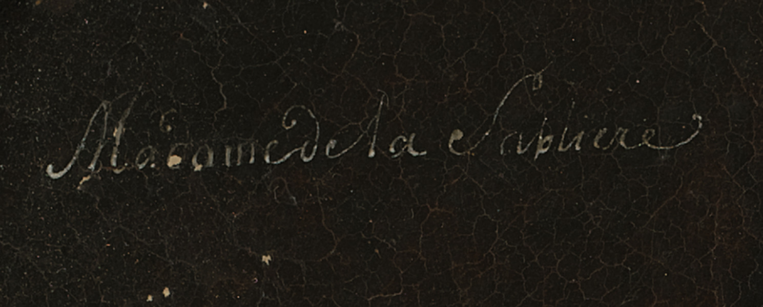 Fragment lica obrazu - napis białą farbą kursywą: Madame de la Sablliere. Tło ciemnobrązowe.