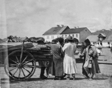Fotografia czarno-biała przedstawia rozmawiających mężczyzn na rynku w Biłograju.