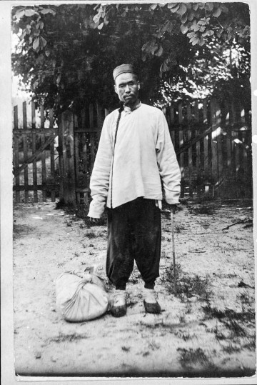 Fotografia czarno-biała przedstawia stojącego mężczyznę o azjatyckich rysach twarzy.