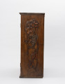 Szafka wisząca - ujęcie z prawego boku; Bok drewnianej prostopadłościennej wiszącej szafki. Ściana szafki zdobiona wzorem z kiści winogron.