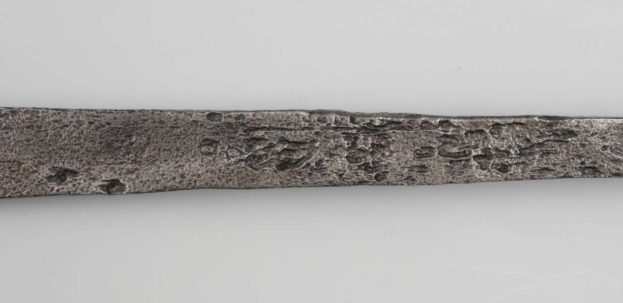 Miecz dwuręczny typu XVII (Oakeshott) - detal; Widoczny fragment żelaznego, srebrnego miecza. Fragment głowni miecza.
