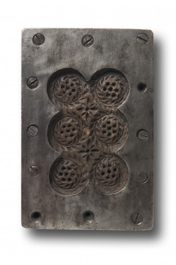 Jedna ze stron formy z negatywowym rytem przedstawiającym piernik Katarzynkę składający się z sześciu ozdobnych medalionów ustawionych parami w trzech rzędach. Płaska powierzchnia formy pokryta wzmacniającą metalową blaszką. 