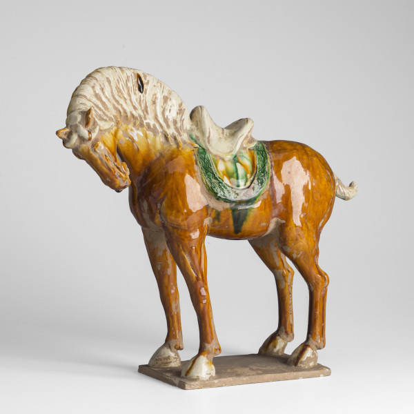 Stojący ceramiczny koń z łbem zwróconym w lewo. Łeb nieco spuszczony ogon podwiązany.