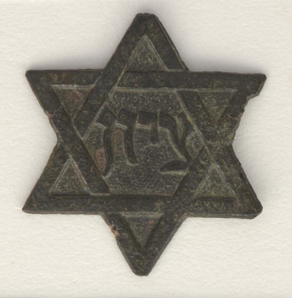 Emblemat wykonany z metalu w kształcie gwiazdy sześcioramiennej (gwiazda Dawida). W centralnym miejscu gwiazdy umieszczono napis w języku hebrajskim: ציון (pol. Syjon).