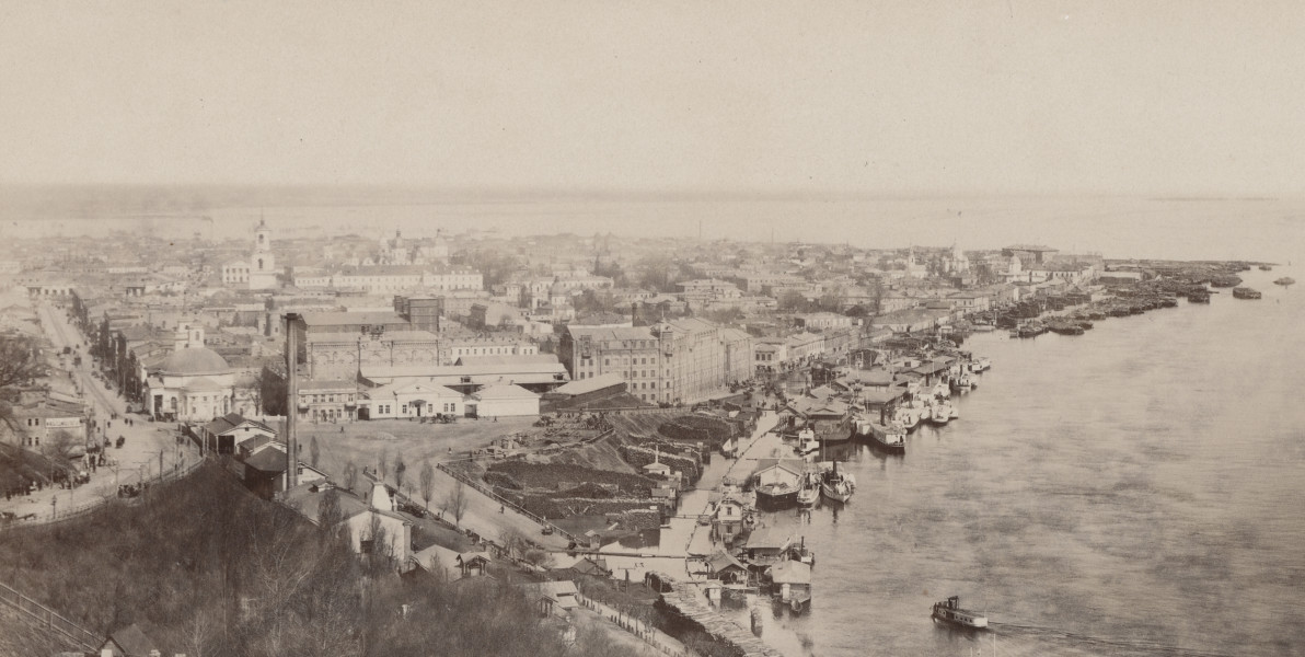 zbliżenie na widok miasta i nabrzeże Dniepru. Po prawej liczne barki i łodzie na rzece, po lewej zabudowa miejska