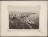 pośrodku białej karty zdjęcie z lotu ptaka na panoramę miasta. Dookoła fotografii drukowana ramka, zdobiona w narożnikach geometrycznym wzorem 