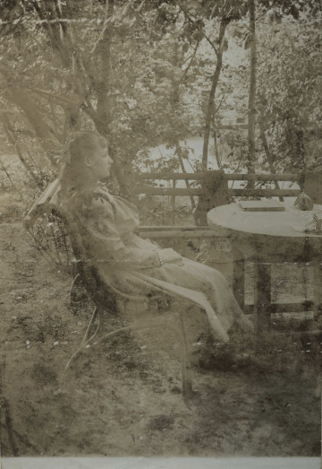 Na zdjęciu znajduje się dziewczynka na ławce, przy stole, w parku.
