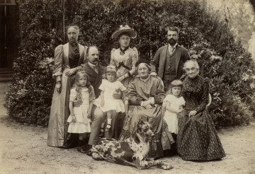 Na zdjęciu znajduje sie grupa osób, sześcioro dorosłych oraz troje dzieci; przed nimi siedzi pies.