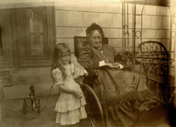 Fotografia przedstawia 4-5 letnią dziewczynkę stojącą obok starszej kobiety.