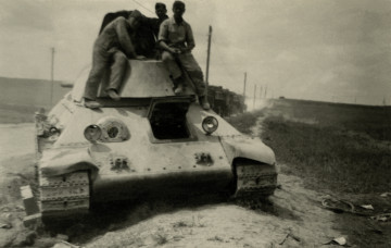 Na zdjęciu znajduje się czołg, na ktorym siedzi trzech mężczyzn.