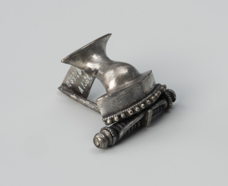 Zapinka ze srebra - ujęcie z przodu; Srebrna fibula z grzebykiem nad sprężynką zdobionym filigranem.