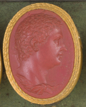 czerwona owalna gemma w grubym złotym obramowaniu; prawy profil mężczyzny z krótkimi kędzierzawymi włosami i widocznym fragmentem szaty; prawej strony sygnatura twórcy: CAVLO COSTANSCE (CARLO COSTAZI)