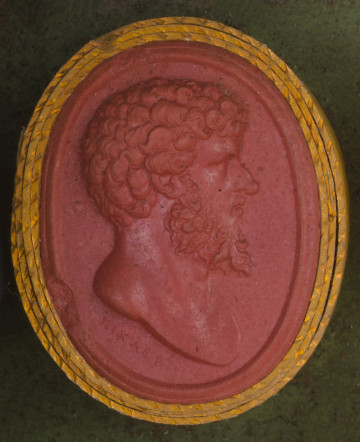 czerwona owalna gemma w grubym złotym obramowaniu; prawy profil mężczyzny w średnim wieku, ma krótkie gęste kręcone włosy i gęstą brodę, pod przecięciem torsu sygnatura: illXAEP (PICHLER)
