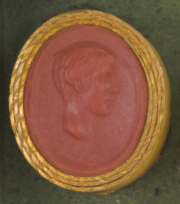 czerwona owalna gemma w grubym złotym obramowaniu; prawy profil młodego mężczyzny z krótkimi,lekko falowanymi włosami; po lewej stronie na obwodzie widoczny napis: MARTIALIS