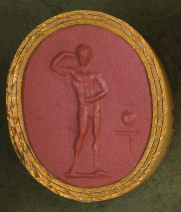 czerwona owalna gemma w grubym złotym obramowaniu; nagi umięśniony mężczyzna widziany na wprost, prawą ręke ma uniesioną, lewą za pomocą ściągaczki zmywa olej z ciała, po prawej widoczny stolik, a na nim dzban