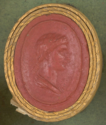 czerwona owalna gemma w grubym złotym obramowaniu, głowa kobiety widoczna z prawego profilu, kobieta ma włosy upięte z tyłu, poniżej szyi widoczny fragment szaty