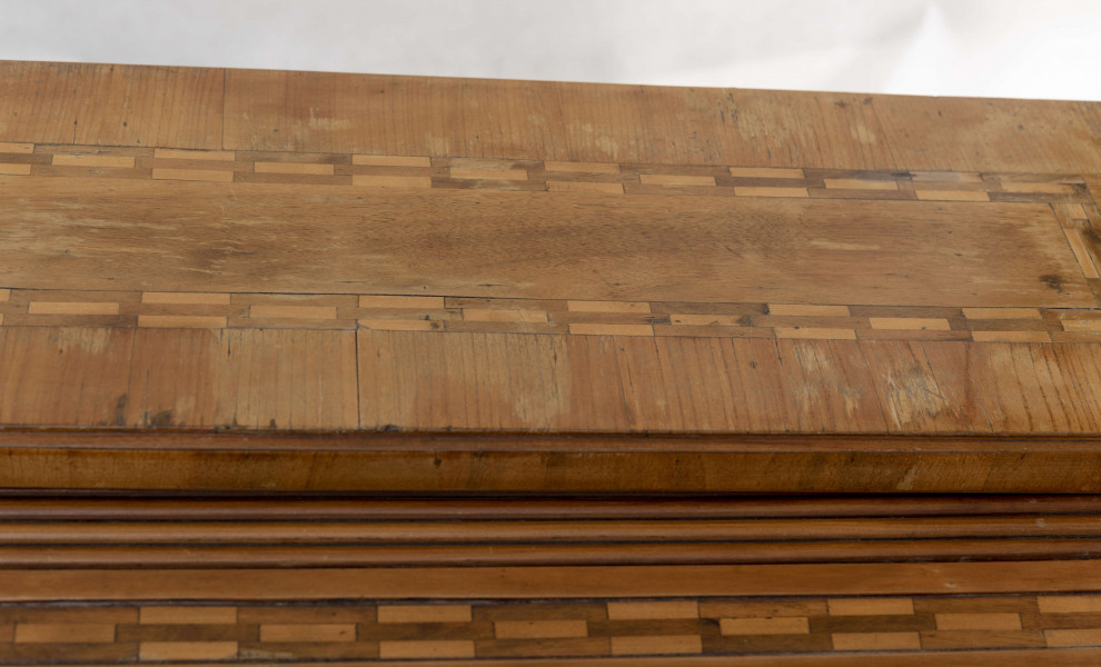 Biurko przyścienne na sześciu nóżkach graniastych zbieżnych. W części dolnej prostokątny prześwit zamknięty tylną ścianą. Po jego bokach po dwie szuflady, powyżej jeszcze trzy. Część górna ćwierćcylindryczna zamykana żaluzją chowaną pod górna płytą powyżej pięciu szufladek, boki zdobione plastycznym ornamentem cekinowym. Lico pokryte fornirem z intarsją ramkową i wzorem arkadkowym. Blat wyłożony skórą cielęcą. Uchwyty szuflad zewnętrznych i żaluzji to nałożone okucia okrągłe z tarczą, szufladki w części górnej mają uchwyty okrągłe z gładką główką.  