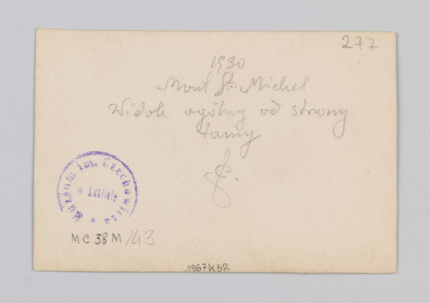 MC/M/38/43/ML - Fotografia w pozycji poziomej. Na zdjęciu uwieczniono widok ogólny na górę Mont Saint-Michel z górującym nad nią opactwem. Po prawej znajduje się ziemna grobla łącząca wyspę z kontynentem, po lewej wody rzeki Couesnon.
Na odwrocie w prawym górnym rogu napis ołówkiem: 