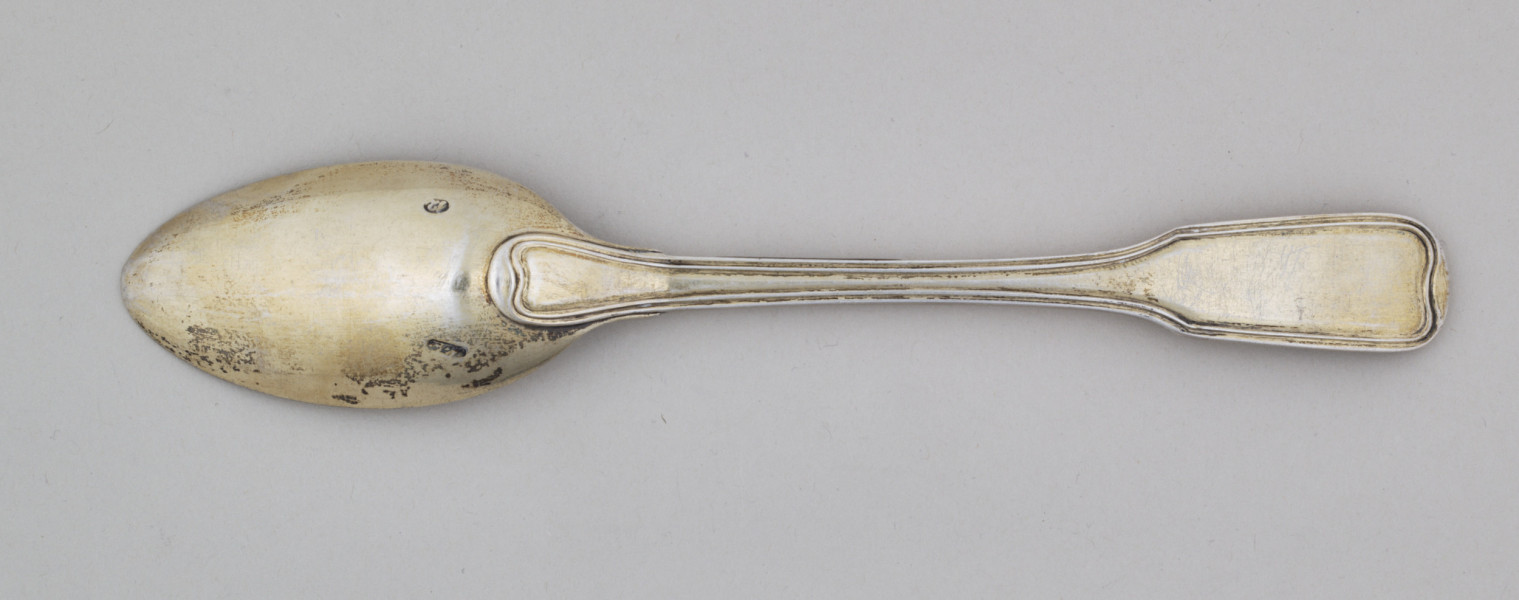 Łyżka obiadowa o głębokiej owoidalnej czarce. Trzonek płaski, lekko wygięty, rozszerzający się przy zakończeniu, ozdobiony przy krawędzi z obu stron podwójnym profilowaniem