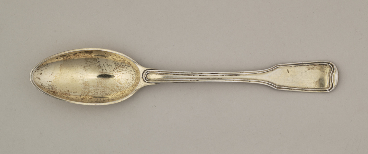 Łyżka obiadowa o głębokiej owoidalnej czarce. Trzonek płaski, lekko wygięty, rozszerzający się przy zakończeniu, ozdobiony przy krawędzi z obu stron podwójnym profilowaniem