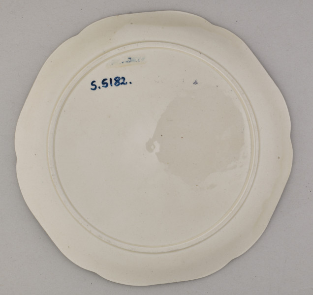 Talerz fajansowy, płytki o łagodnie podniesionym brzegu, wykrojonym w sześć płaskich łuków. Dekoracja reliefowa wklęsło-wypukła przedstawia kaczkę stojącą na niewielkim cyplu wśród wodnego krajobrazu