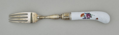 Widelec śniadaniowy, czterozębny. Zęby wygięte, zwężające się przy zakończeniu. Trzonek z nakładką ze srebra złoconego z białej porcelany