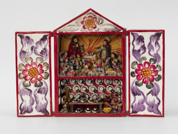 retablo - Ujęcie z przodu; Jasna, bogato dekorowana kolorowymi wzorami florystycznymi, prostopadłościenna, wewnątrz dwupoziomowa skrzynka (kapliczka) z dwuskrzydłowymi drzwiczkami, zwieńczona trójkątną koroną. Na wyższym poziomie pokazano Narodzenie Dzieciątka Jezus, gdzie wykonane z pasty ziemniaczanej i gipsu, polichromowane postacie Marii, Józefa i malutkiego Jezusa ustawiono na podwyższeniu. Bezpośrednio za Świętą Rodziną znajdują się zwierzęta: osioł i krowa. Poniżej głównych (nieco większych od pozostałych) figur zaprezentowano miejscową ludność (kobiety, mężczyzn i dzieci) w pozycji modlitewnej – większość klęczy z dłoniami złożonymi i skierowanymi ku Dzieciątku. Pierwszy rząd wypełniają najmniejsze figurki zwierząt hodowlanych: kóz, owiec, cieląt, jagniąt, krów, kur, źrebiąt oraz kota. Tło przedstawienia składa się z dwóch różnych dekoracji. Po obu bokach zastosowano wzór kropkowy (wielokolorowy) na białym tle, natomiast centralnie za postaciami namalowano usytuowane nisko na horyzoncie czerwone słońce na żółtym tle. Dolne piętro przedstawia scenę rodzajową: sprzedawcę kapeluszy w sklepie lub na targu w towarzystwie miejscowej ludności, instrumentów muzycznych i prawdopodobnie psa. Różowe tło wypełniono trzema rzędami figurek przedstawiających biało-czarne kapelusze typu panama.