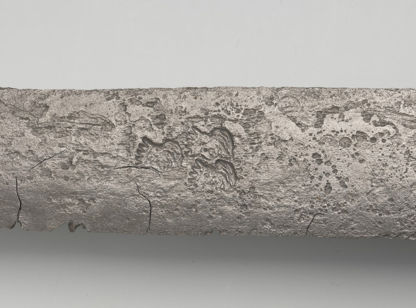 rapier - detal; na głowni poniżej zbrocza obustronnie, 	trzy głowy brodatego króla w układzie jedna u góry, dwie na dole, zwrócone w jedną stronę