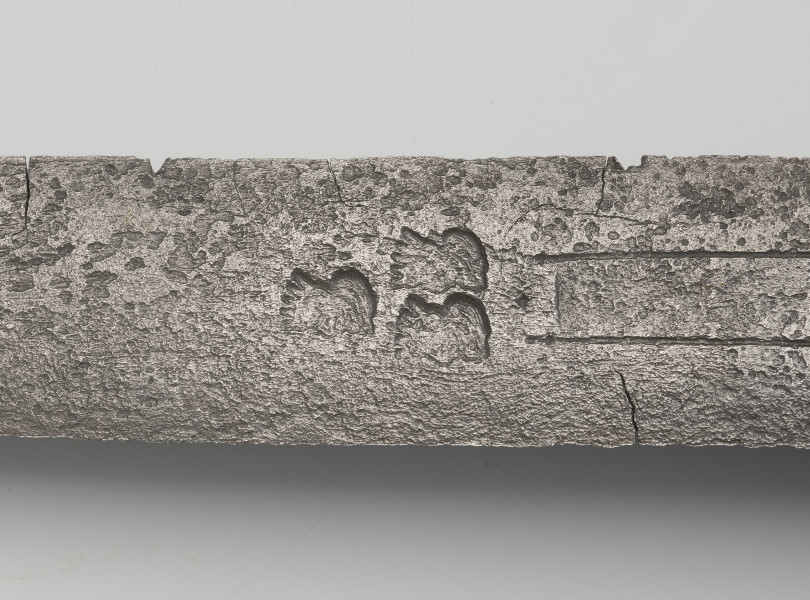 rapier - detal; na głowni poniżej zbrocza obustronnie trzy głowy brodatego króla w układzie jedna u góry, dwie na dole, zwrócone w jedną stronę