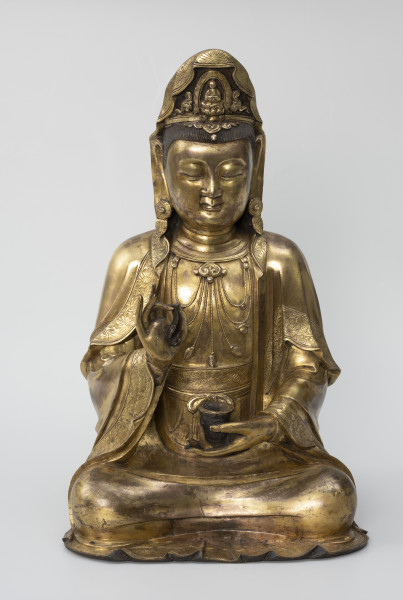 Bodhisattwa Guanyin - ujęcie z przodu; Duża, wykonana ze złoconego brązu figura przedstawia siedzącą w pozie medytacyjnej kobietę Bodhisattwę Guanyin (chin. 观音, sanskr. Awalokiteśwara, tyb. Czenrezig). Postać ma spuszczone, przymknięte oczy, symetryczną, pełną twarz o pogodnym i spokojnym wyrazie oraz gładko zaczesane włosy, schowane pod diademem i zaciągniętą na głowę tkaniną. Ubrana jest w długie, warstwowe, jedwabne szaty królewskie oraz wyszukaną, ciężką biżuterię książęcą: diadem, w którego centrum znajduje się niebiański Budda Amitabha (sanskr. Amitābha); pary dużych, okrągłych kolczyków ze spiczastymi zawieszkami oraz grubego naszyjnika z klejnotem, od którego odchodzi siedem pasów korali z wisiorkami. Jej prawa dłoń uniesiona na wysokości klatki piersiowej ułożona jest pionowo, jej środkowy palec i kciuk tworzą okrąg trzymając niezidentyfikowany, haczykowaty przedmiot. Poniżej znajduje się ustawiona poziomo lewa dłoń, która ściska niewielką wazę.
