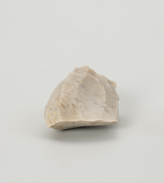 rdzeń stożkowy - Ujęcie z góry; Rdzeń z bryły krzemienia kredowego bardzo wysokiej jakości w końcowym stadium eksploatacji o znacznym stopniu redukcji uniemożliwiającym jego utrzymanie. Forma zbliżona do stożka lub ostrosłupa o dookolnej odłupni. Widoczny na jednej ze stron duży negatyw wskazuje na naprawę rdzenia krótko przed zakończeniem eksploatacji. W masie widoczne są liczne długie egzoszkielety organizmów morskich, ułożone w podłużne linie. Zabytek w całości pokryty jest białą patyną wskazującą na długotrwałe zaleganie na powierzchni.