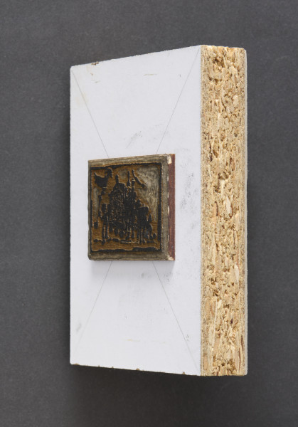 klocek drzeworytniczy - Klocek drzeworytniczy przedstawiający grupę postaci z wozem. Klocek drewniany, z wyrytym tłem tworzącym wypukłą powierzchnie odbicia matrycy przedstawiającą grupę postaci z wozem oraz człowiekiem trzymającym podłużny przedmiot zakończony kształtem ptaka. Matryca przymocowana do prostokątnego kawałka płyty wiórowej z naklejonym od przodu białym laminatem oraz szarą tekturą od tyłu.