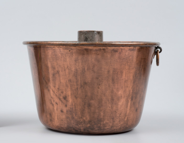 strona druga - ujęcie z boku przy ustawieniu spodem do góry. Komin wystający ponad brzeg naczynia. Uchwyt do zaczepienia po prawej.