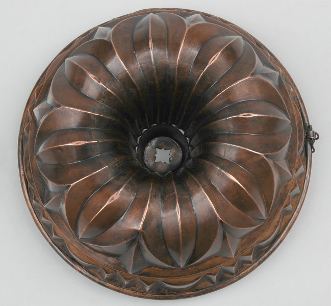 ujęcie z góry. Naczynie o półkulistej formie z wgłębieniem pośrodku. Powierzchnia ukształtowana w rozłożoną ośmioczęściową rozetę.