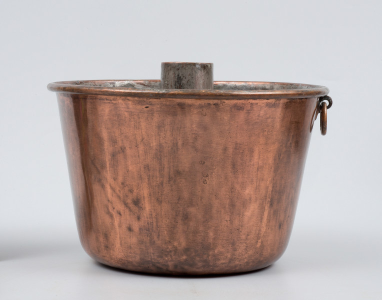 strona druga - ujęcie z boku przy ustawieniu spodem do góry. Komin wystający ponad brzeg naczynia. Zaczep z kółkiem po prawej.