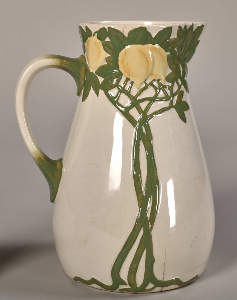 Dzbanek toaletowy, mały, zdobiony gałązkami i owocami cytryny. Widok na dekorację roślinną i uchwyt z lewej strony.