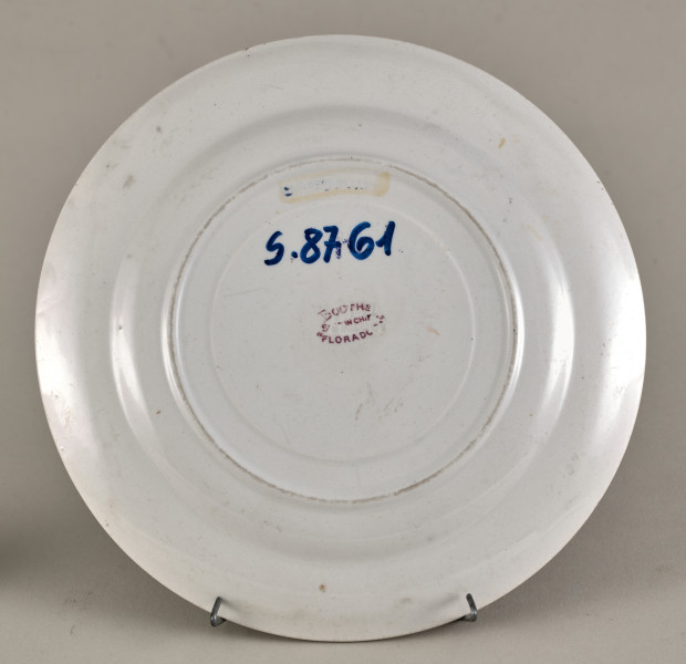 Mały, płytki talerzyk wykonany z białego fajansu. Stanowi podstawkę pod sosjerkę